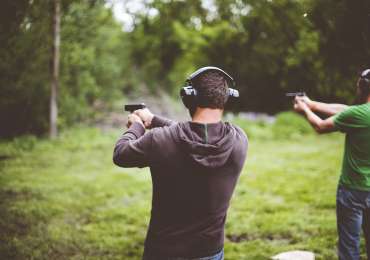 Shallow focus shot of people shotting guns in nature